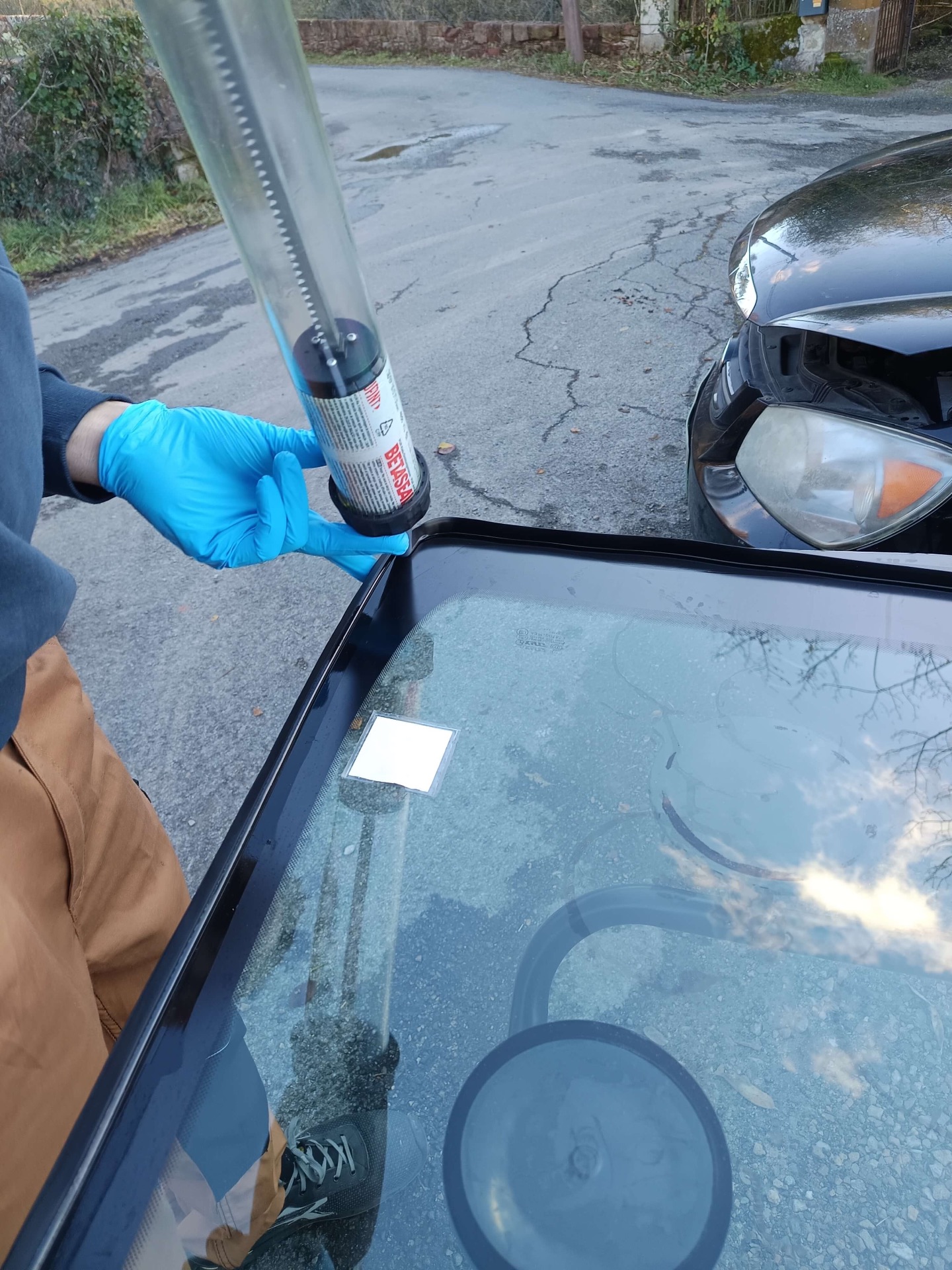 Application d'un cordon de colle professionnel sur le pourtour du nouveau pare-brise
